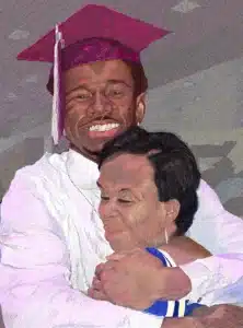 Smiling graduate in a pink cap hugs a friend, celebrating after graduation with a joyful embrace.
